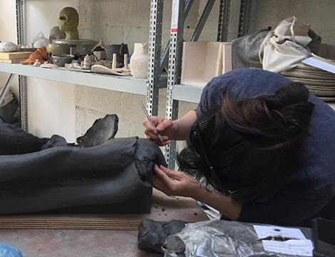 céramiste au travail dans son atelier façonnant une oeuvre de céramique contemporaine.